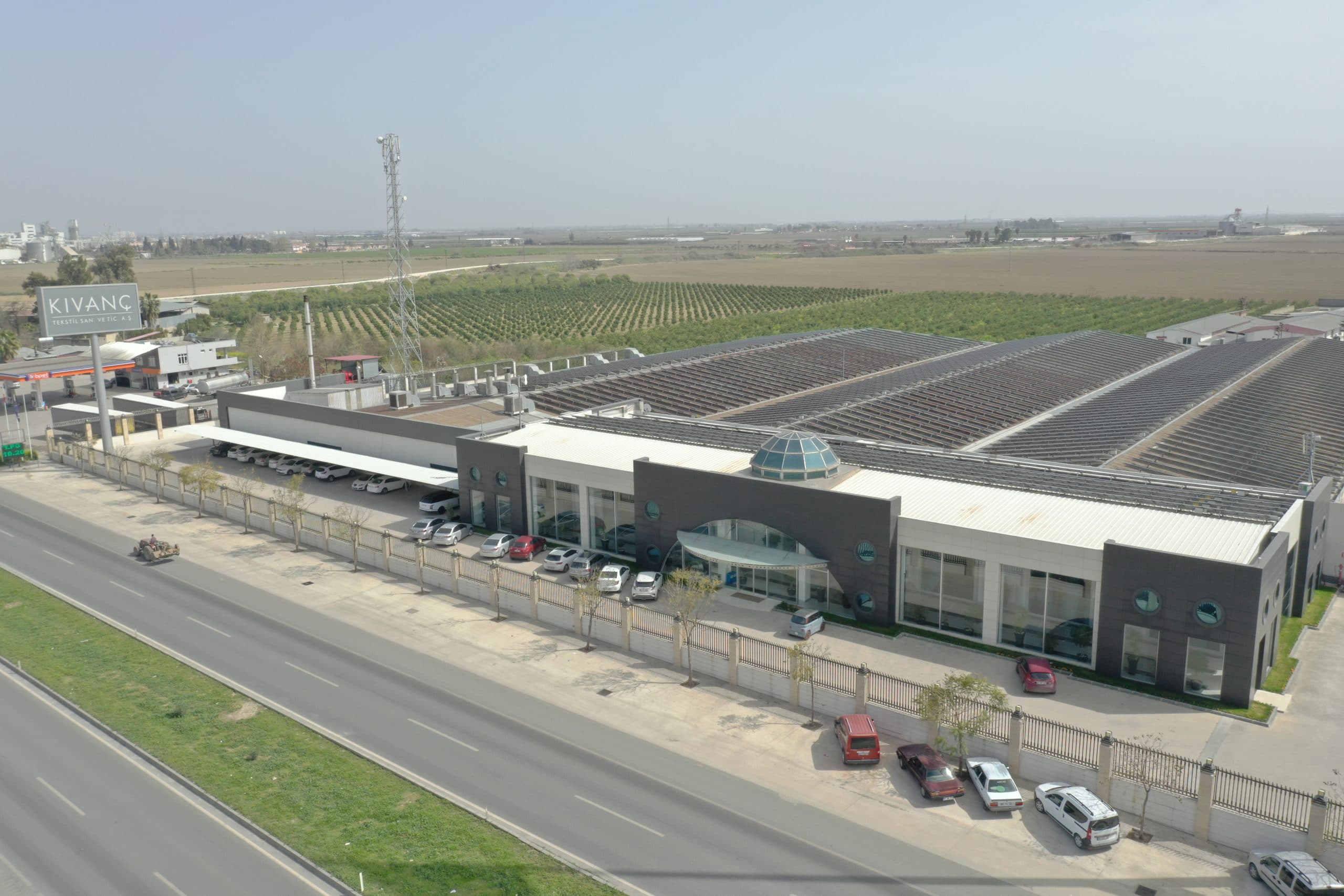 Kıvanç Tekstil fabrikasının karayolu cephesi: antrasit panelli idari blok, cam kubbe ve geniş üretim holleri