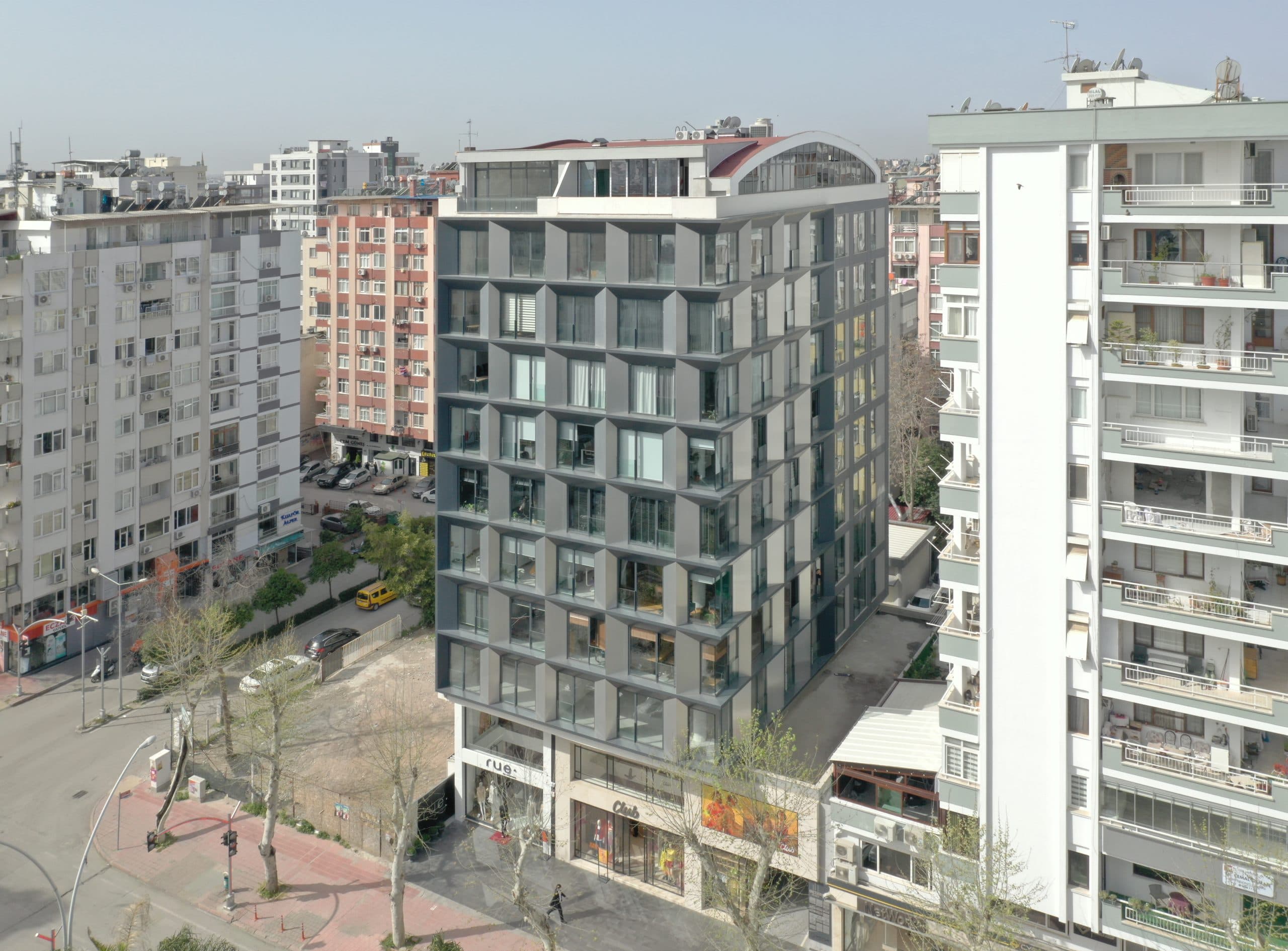 Ziyapaşa Plaza, gri kompozit çerçeveli pencereler ve kavisli cam çatı katı, drondan üç çeyrek görünüm