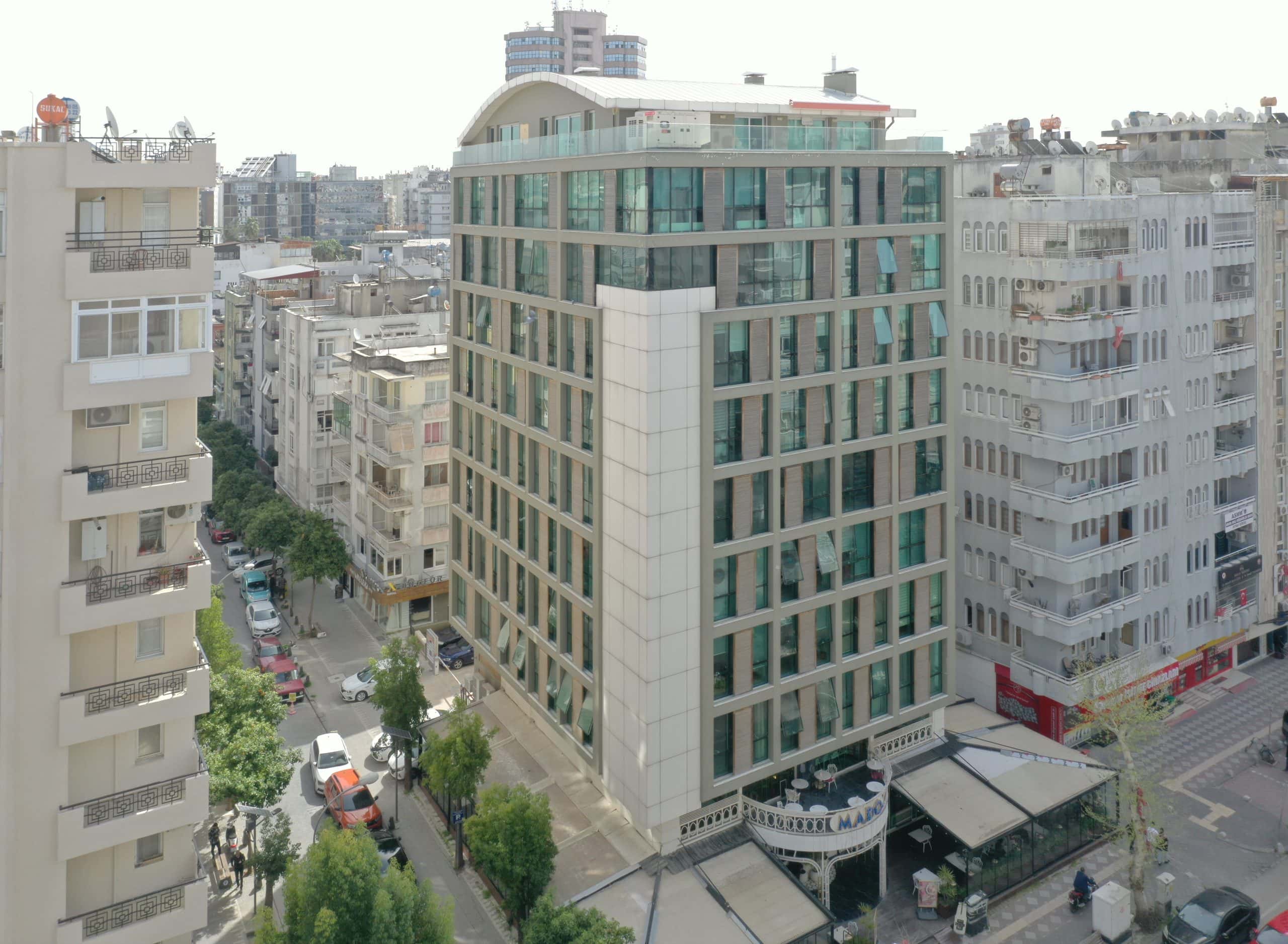 Bulvar İş Merkezi köşeden havadan: gri panel ızgaralı cephe, krem köşe kütlesi ve kavisli çatı katı
