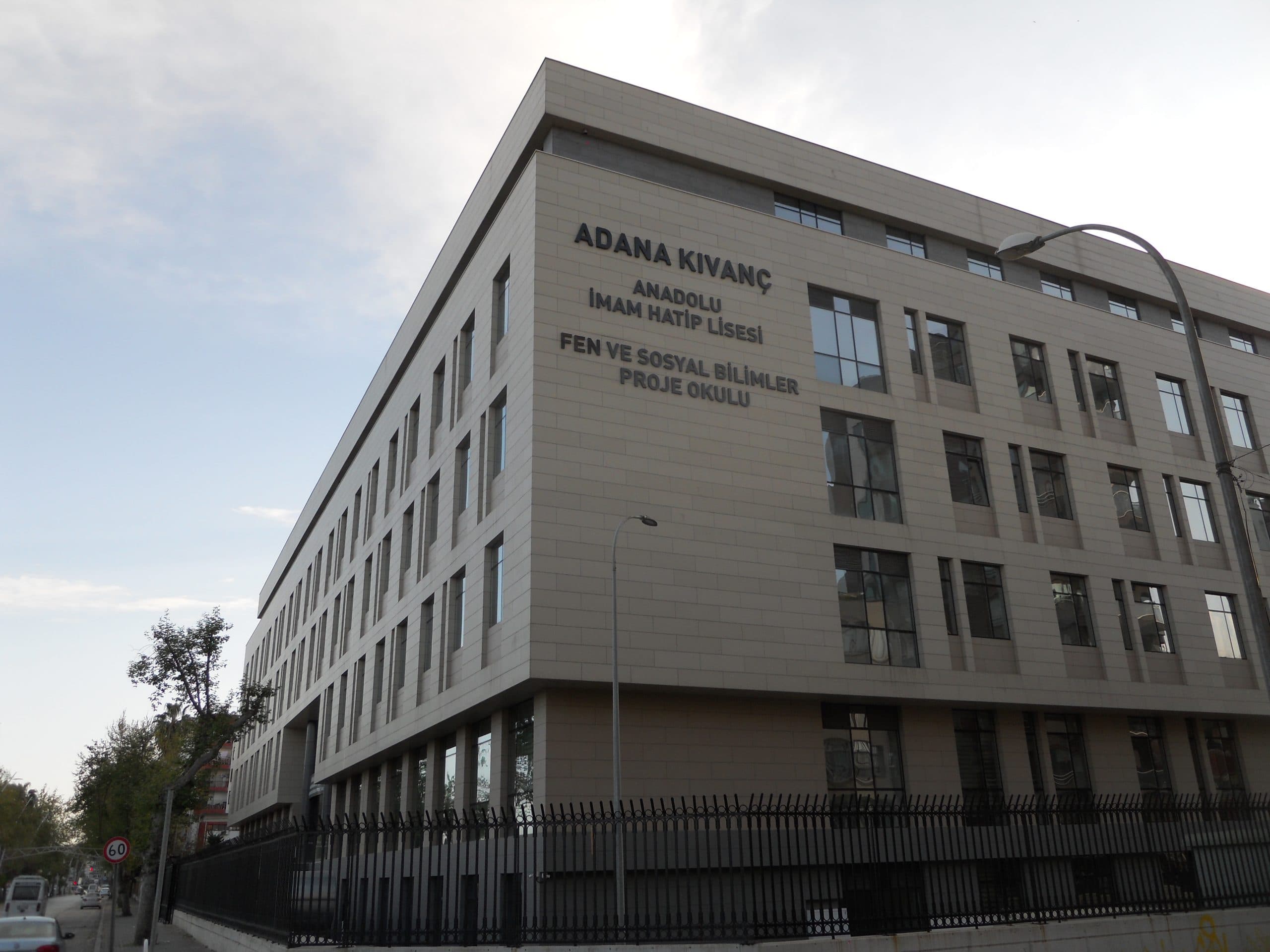 Köşeden aşağıdan bakış: 'Adana Kıvanç Anadolu İmam Hatip Lisesi' harfleri ve şaşırtmalı derzli cephe paneli