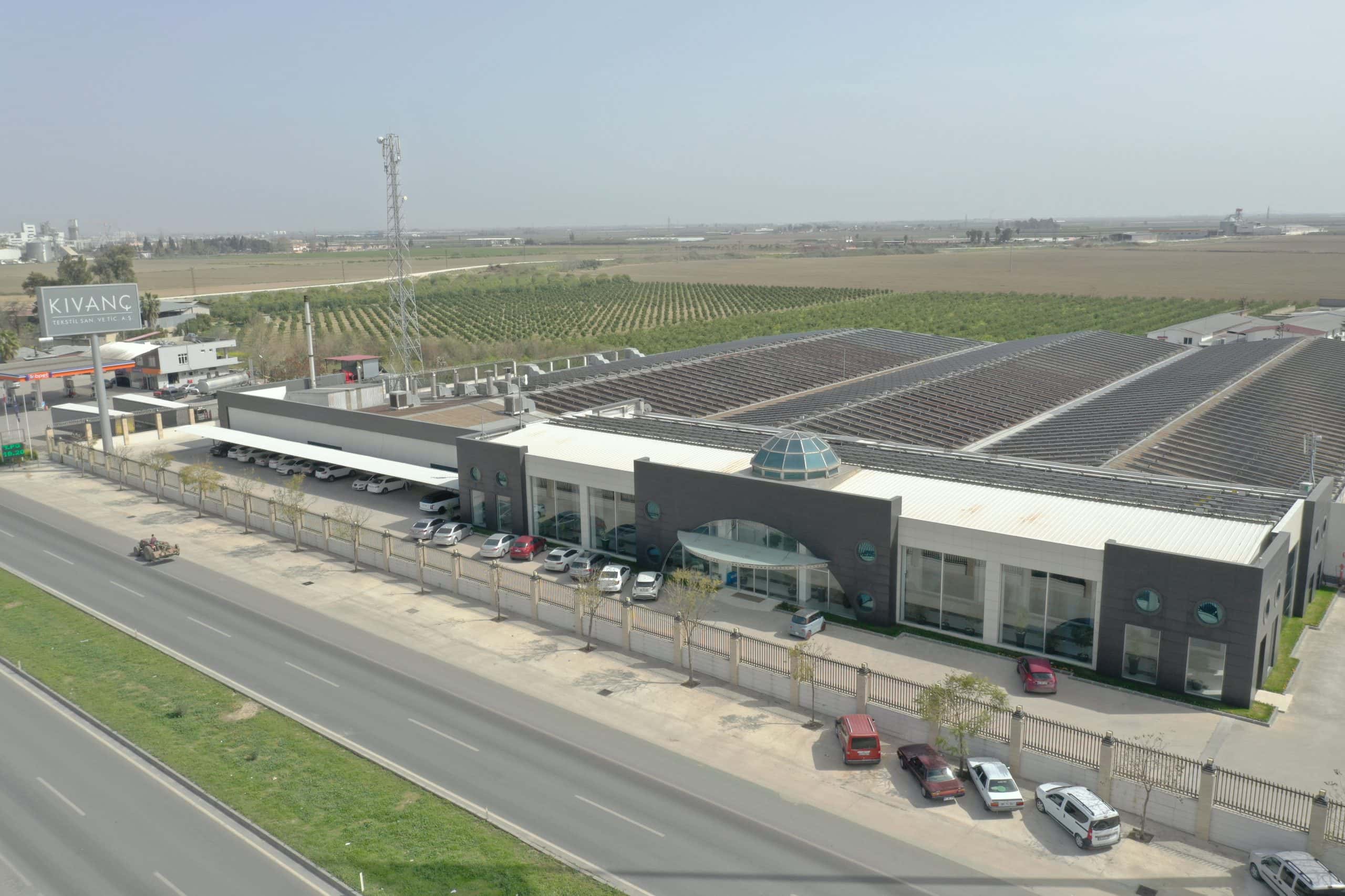Kıvanç Tekstil fabrikasının karayolu cephesi: antrasit panelli idari blok, cam kubbe ve geniş üretim holleri