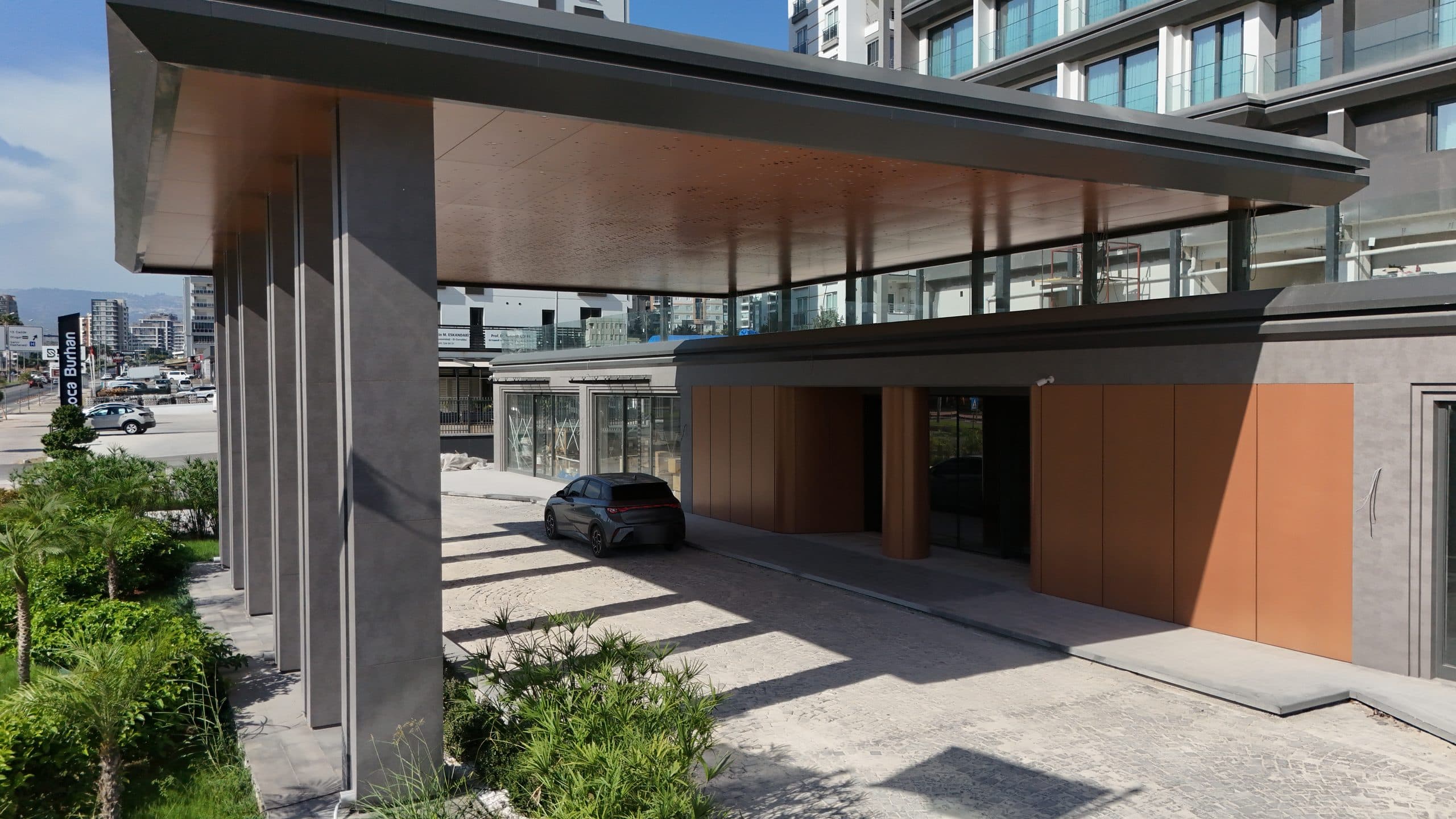 Ramada Plaza saçağının altı: bakır renkli tavan, gri kolonlar ve bakır panel kaplı giriş duvarı